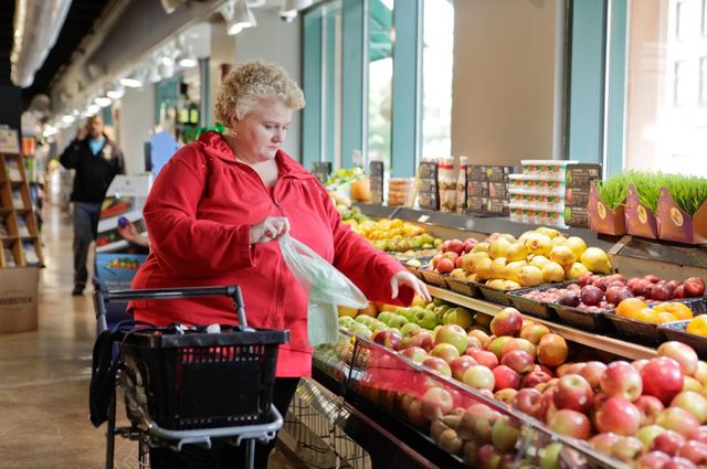 A woman shopping in the produce department of a grocery store.