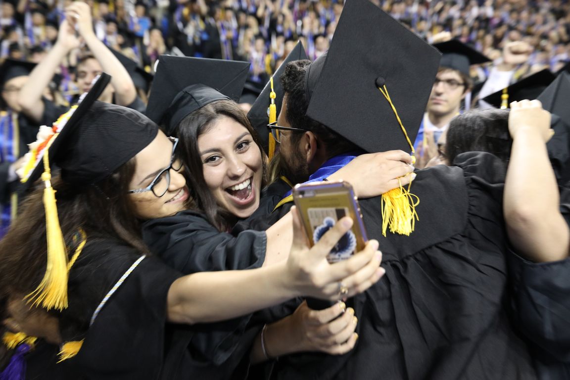 Graduates in Pauley Pavilion taking selfies