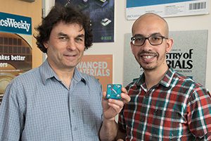 Photo of Richard Kaner, with Maher El-Kady, holding a replica of an energy storage and conversion device the pair developed.