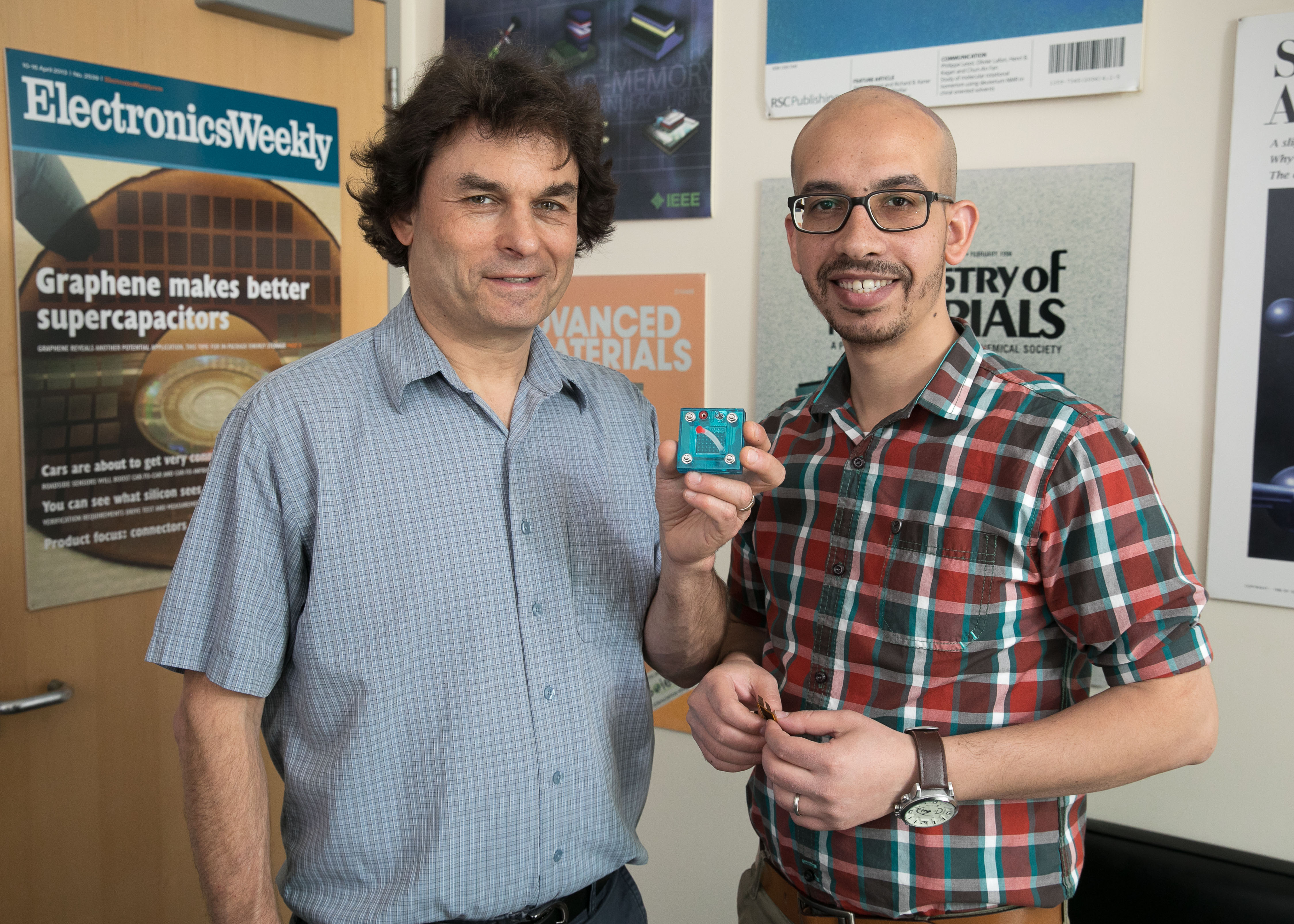Photo of Richard Kaner, with Maher El-Kady, holding a replica of an energy storage and conversion device the pair developed.