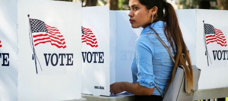 A photo of a woman at a voting booth.