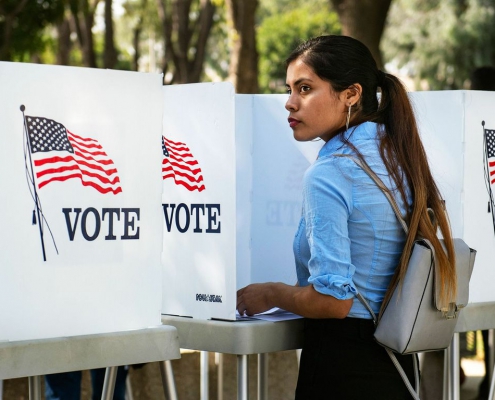 A photo of a woman at a voting booth.