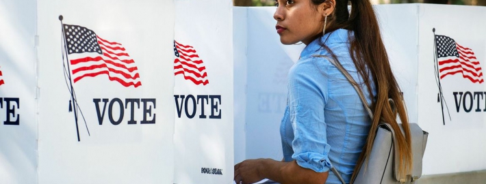 A photo of a woman at a voting booth.