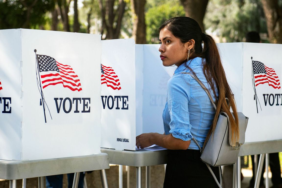 A photo of a woman at a voting booth.