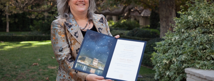 A photo of Andrea Ghez receiving her Nobel Prize citation and medal.