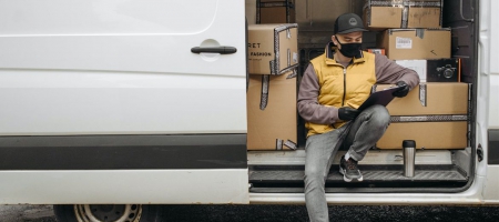 A photo of a worker wearing a face covering on a delivery truck.