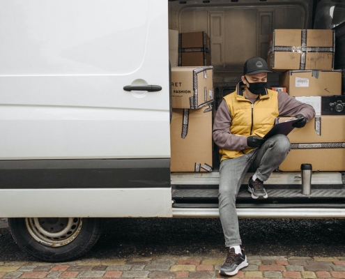 A photo of a worker wearing a face covering on a delivery truck.