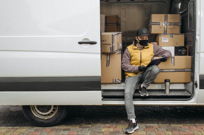 Worker+on+truck+Pavel+Danilyuk+Pexels_hero A photo of a worker wearing a face covering on a delivery truck.