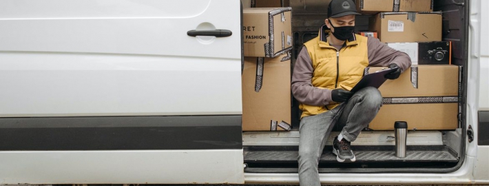 A photo of a worker wearing a face covering on a delivery truck.