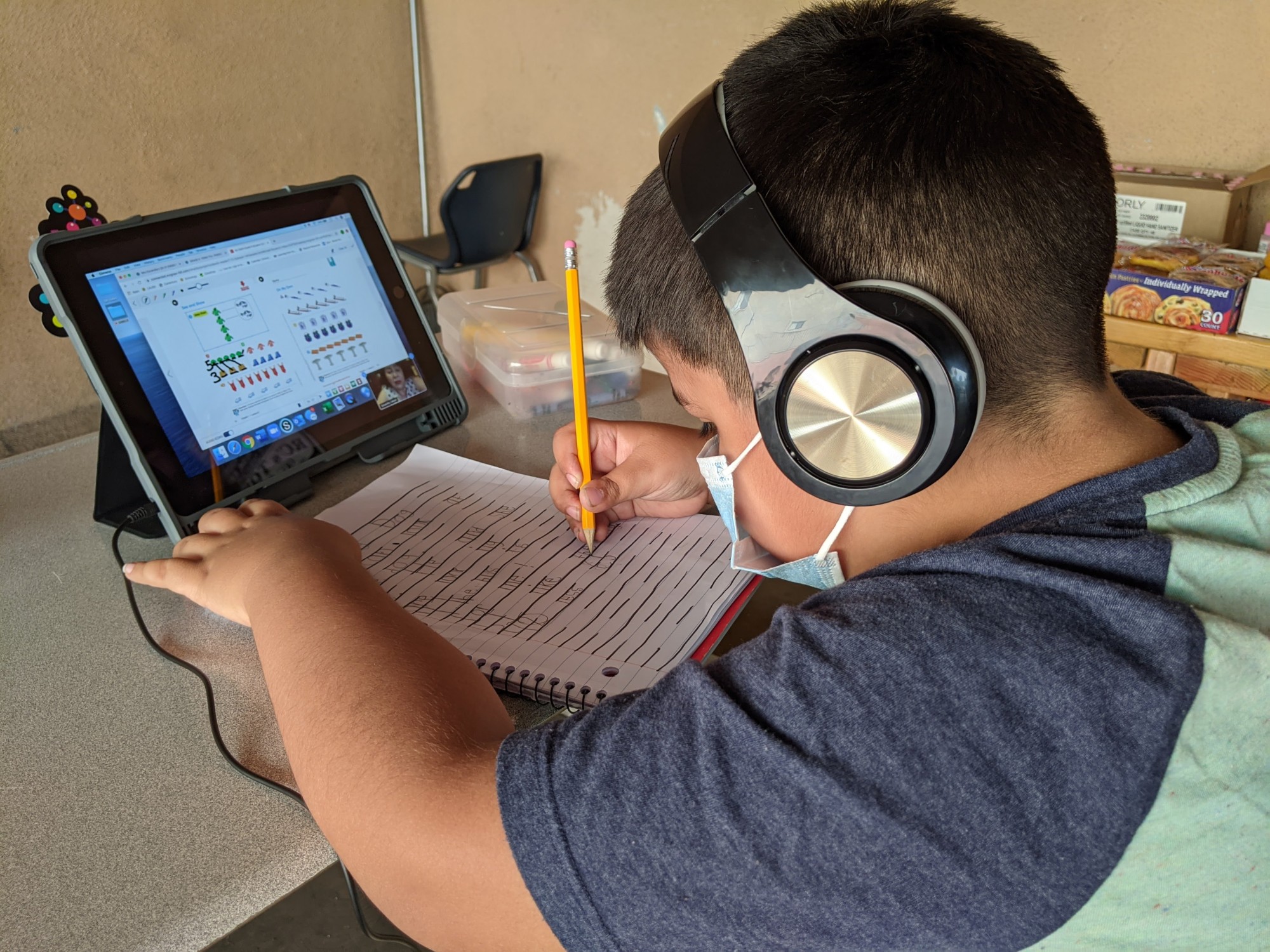 Young boy with school workbook and tablet computer