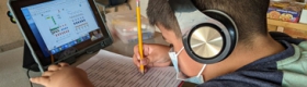 Young boy with school workbook and tablet computer