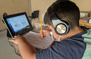 Young boy with school workbook and tablet computer