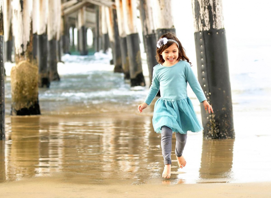 Evangelina Vaccaro playing beneath pier at the beach