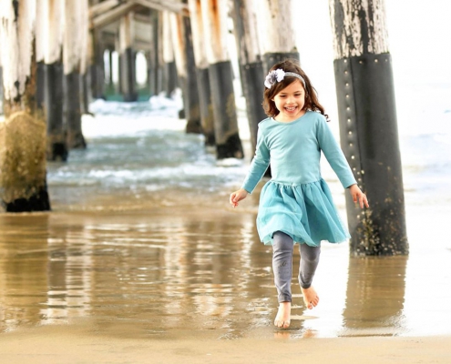 Evangelina Vaccaro playing beneath pier at the beach