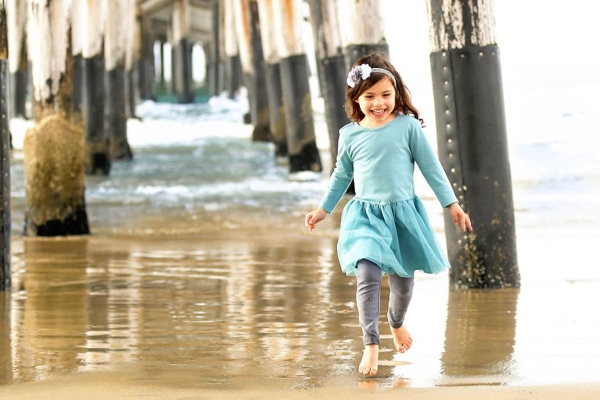 Evangelina Vaccaro playing beneath pier at the beach
