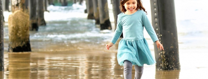 Evangelina Vaccaro playing beneath pier at the beach
