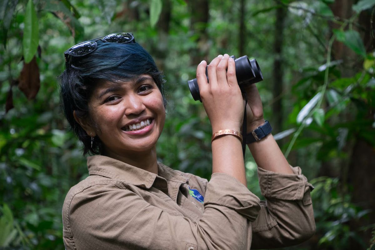 Image of Farwiza Farhan in the field, holding binoculars