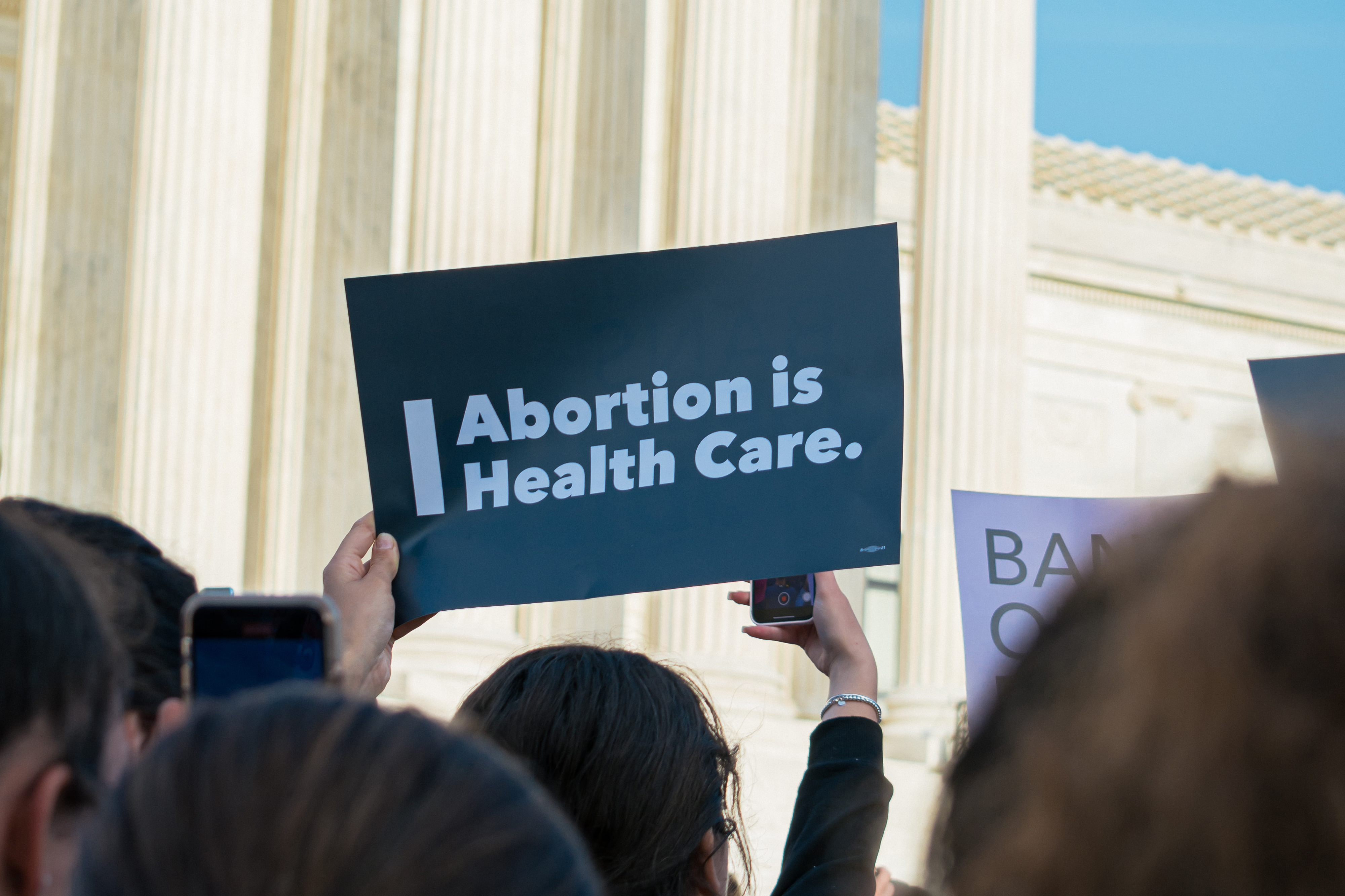 Image of a person holding a sign with text that says ABORTION IS HEALTH CARE