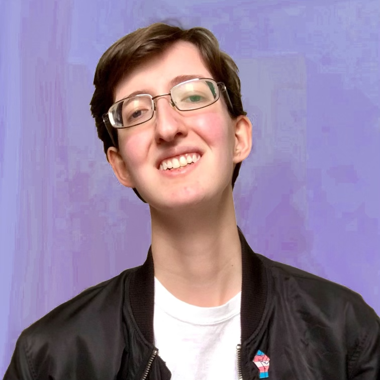 Photo of Christopher, a white genderqueer man with short brown hair, small-framed glasses, a white t-shirt, and a black bomber jacket with a trans pride pin, smiles to the camera in front of a lavender background.