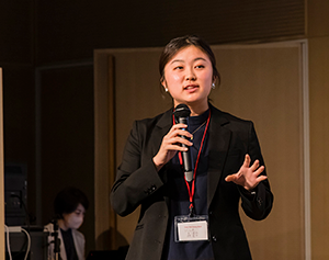 Kanon Mori, wearing a nametag, speaks into a microphone