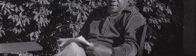 Alex Haley seated in chair in backyard, surrounded by foliage