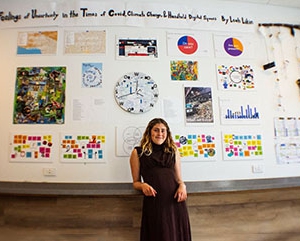 Leah Likin poses in front of a section of the art component of her honors capstone project