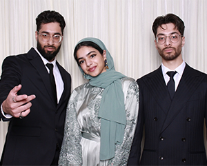 The Farrukh siblings posing against a white wall.