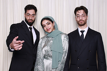 The Farrukh siblings posing against a white wall.