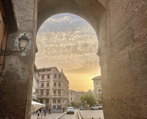 A sunset in Granada descending on stone buildings and a cobblestone road.