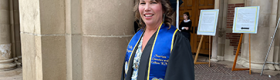 Kelly Kingman in graduation regalia outside of Royce Hall