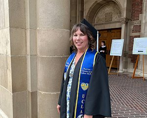 Kelly Kingman in graduation regalia outside of Royce Hall