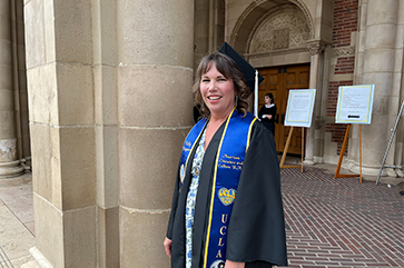 Kelly Kingman in graduation regalia outside of Royce Hall