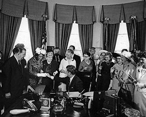 Black-and-white photo of President John F. Kennedy signing the Equal Pay Act