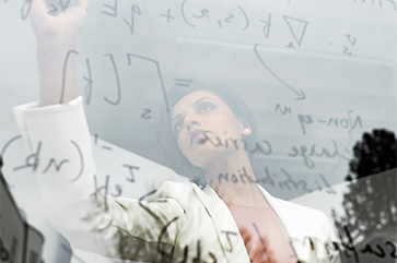 Prineha Narang in a white coat writing equations on a transparent board.