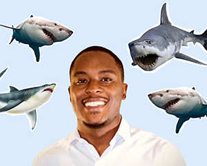 De’Marcus_363 Head and shoulders photo of De'Marcus Robinson smiling against a light blue background with cut-out images of sharks surrounding him.