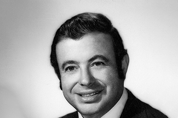 Black and white head and shoulders photo of Wayne Harding smiling.