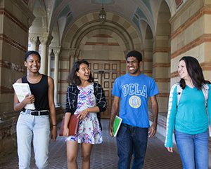 Four students walking side by side in Royce Hall portico