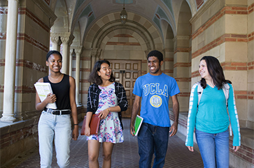 Four students walking side by side in Royce Hall portico