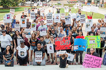 A crowd of people holding signs at a Drop LWOP Coalition event