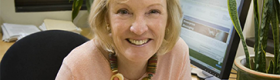 head and shoulders photograph of Shelley Taylor in an office with a computer screen in the background