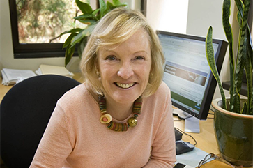 head and shoulders photograph of Shelley Taylor in an office with a computer screen in the background
