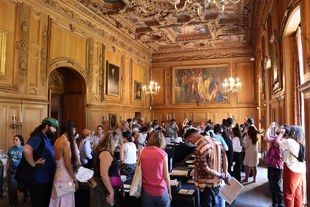 Visitors of the Clark Library browsing through manuscripts in a well lit, ornate wooden room.