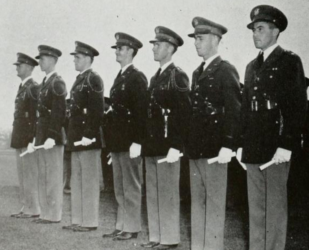 A black and white photograph of seven men in military dress blues standing shoulder to shoulder.