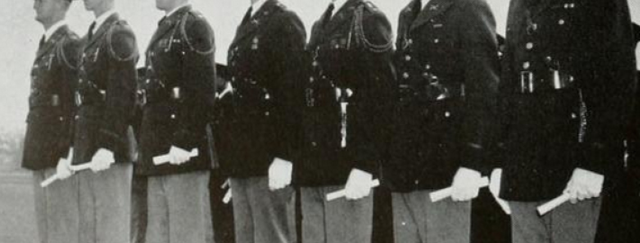A black and white photograph of seven men in military dress blues standing shoulder to shoulder.