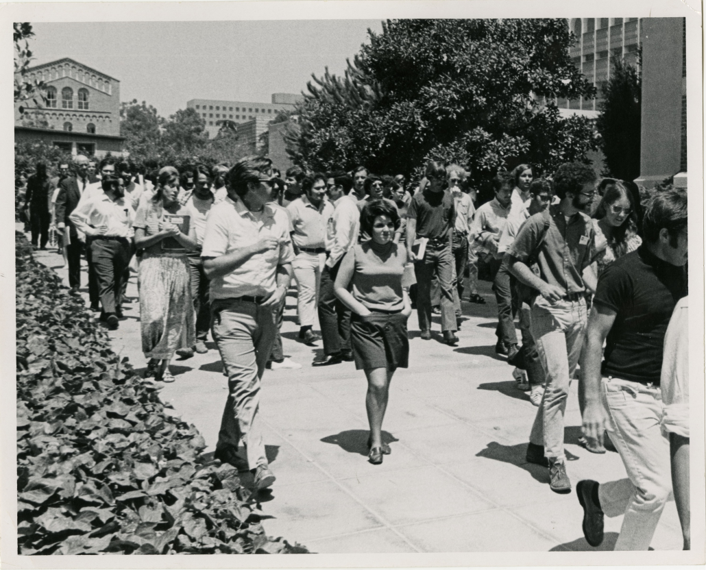 A black and white photograph of students walking through the UCLA campus.