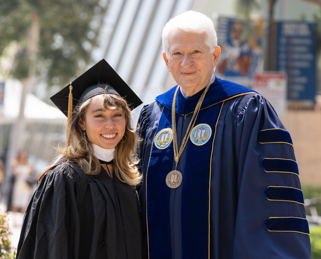 From left to right, gymnast and alumnus Katelyn Ohashi and Chancellor Gene Block in graduation regalia standing outside.