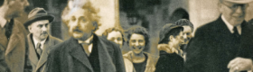 Albert Einstein surrounded by people with stone columns in the background.