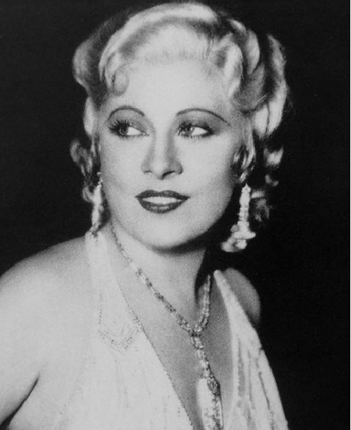 A black and white photograph of Mae West in a white dress.