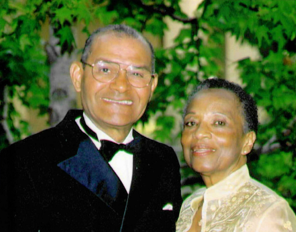 Billy G. Mills (left) and Rubye J. Mills (right) dressed in formal attire with trees and leaves in the background.
