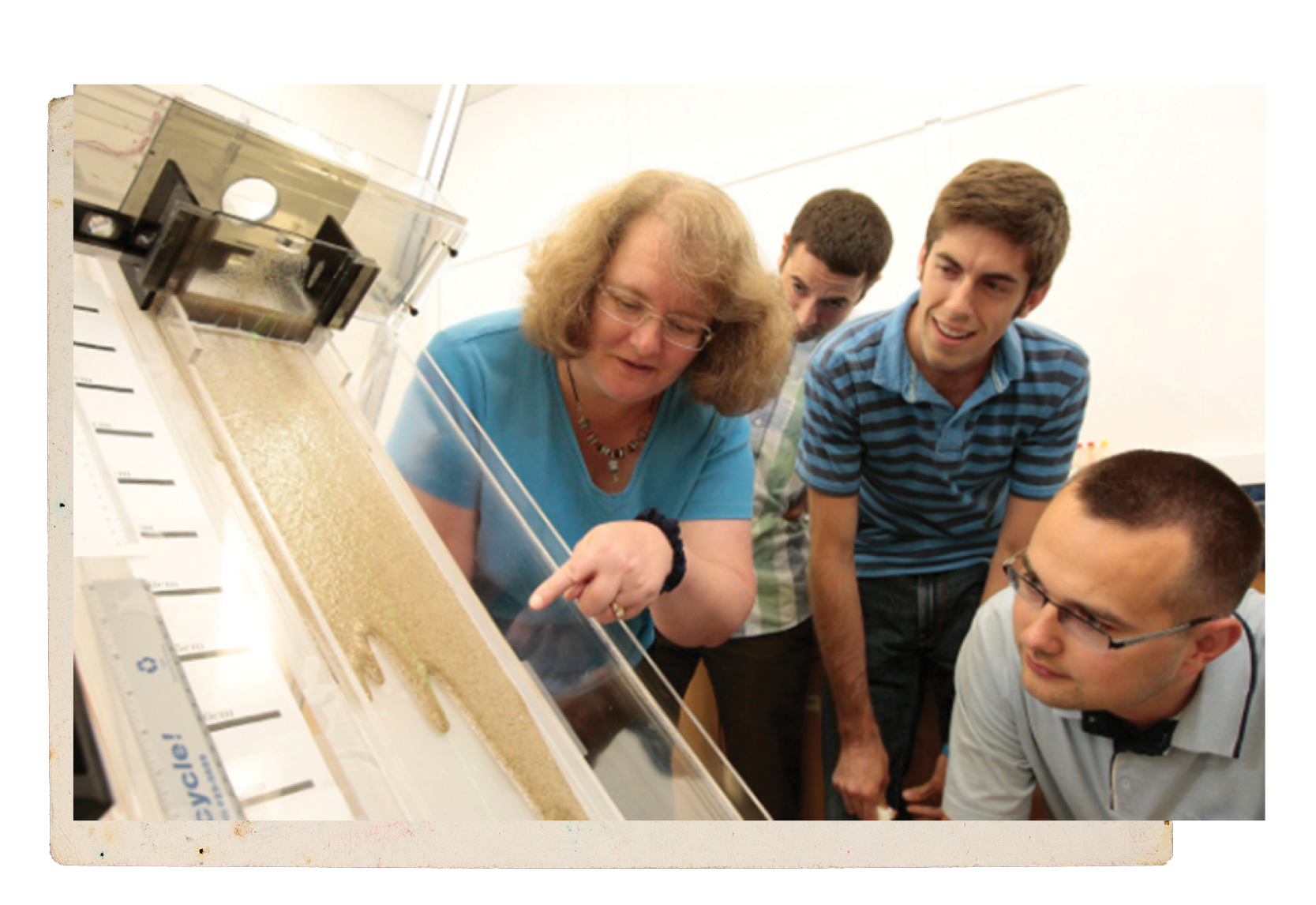 A professor and her students in a lab setting conducting an experiment involving oil and beach sand.